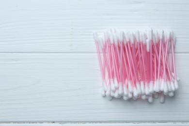 Photo of Many cotton buds on white wooden table, flat lay. Space for text