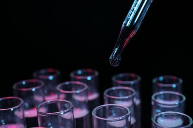 Photo of Dripping reagent into test tube on black background, closeup. Laboratory analysis