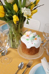 Photo of Festive table setting with traditional Easter cake and vase of tulips