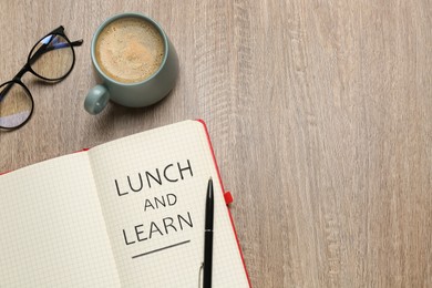 Image of Lunch and Learn concept. Notebook, cup of coffee and glasses on wooden table, flat lay