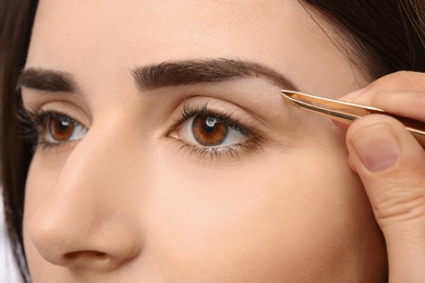 Young woman having professional eyebrow correction procedure, closeup