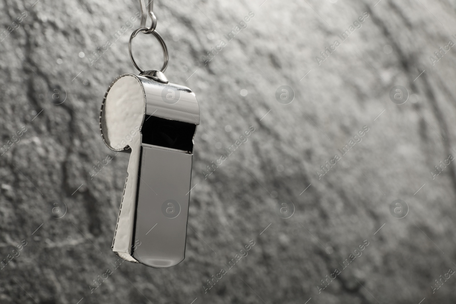 Photo of Referee equipment. Metal whistle on grey textured background, closeup and space for text