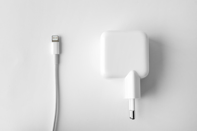 Photo of Charging cable and adapter on white background, top view