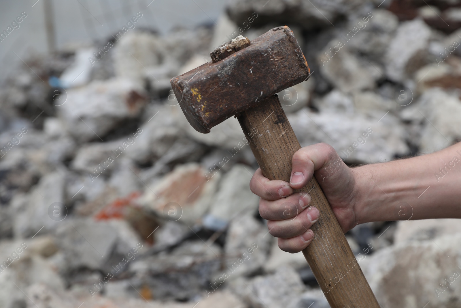 Photo of Man with sledgehammer near pile of stones outdoors, closeup. Space for text