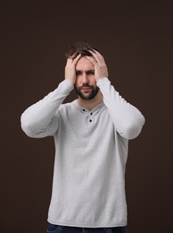 Photo of Man with suffering from headache on brown background. Cold symptoms