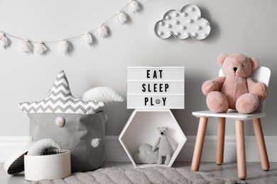 Light box with words Eat Sleep Play and cute toys in baby room. Interior design