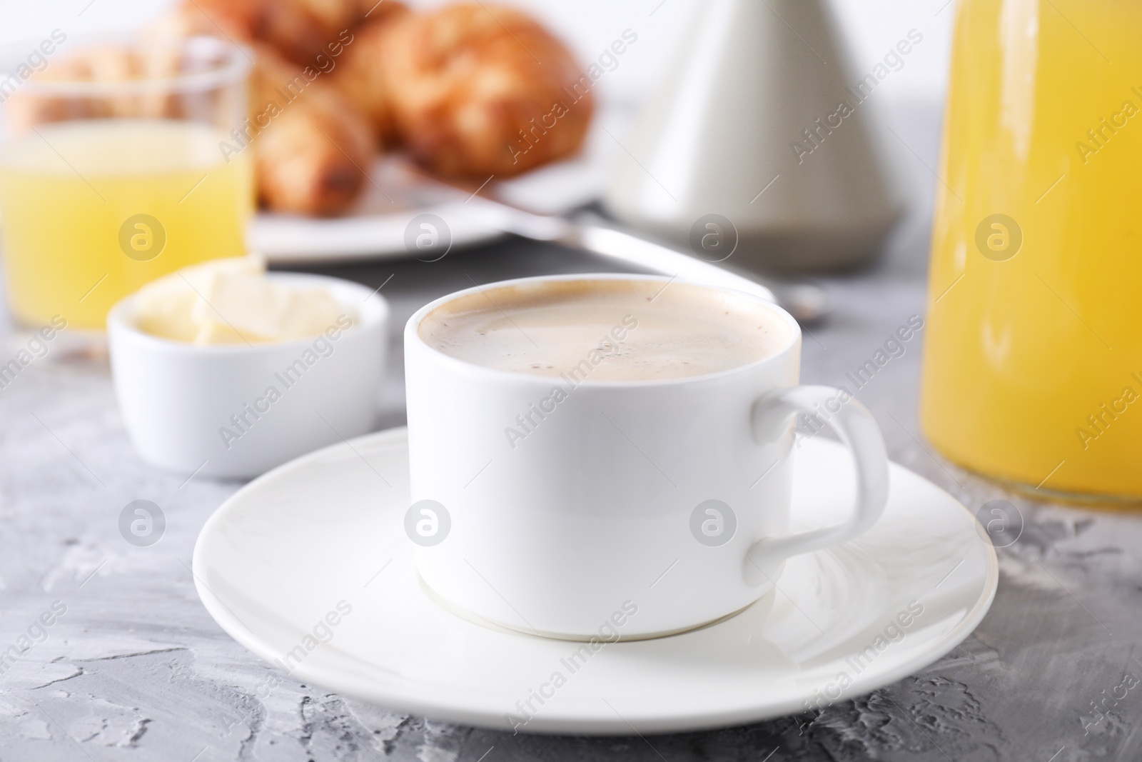 Photo of Tasty breakfast. Cup of coffee and butter on grey table, closeup