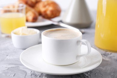 Photo of Tasty breakfast. Cup of coffee and butter on grey table, closeup