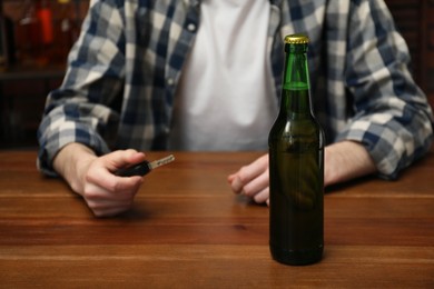Man with car keys at table with bottle of beer, closeup. Don't drink and drive concept