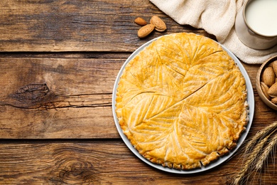 Traditional galette des rois and ingredients on wooden table, flat lay. Space for text