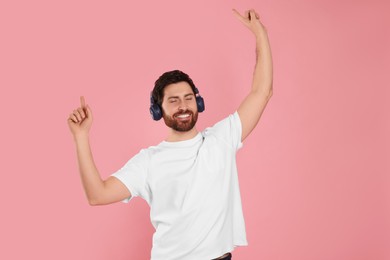 Photo of Happy man listening music with headphones on pink background