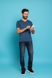 Photo of Handsome man with phone on light blue background