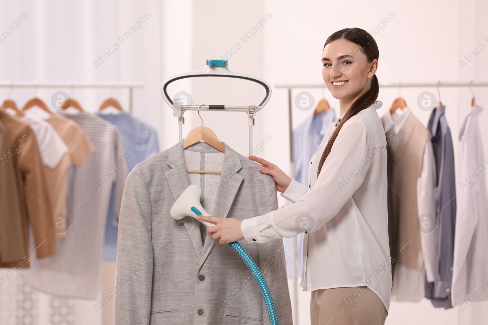 Photo of Woman steaming jacket on hanger in room