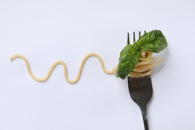 Fork with tasty pasta and basil isolated on white