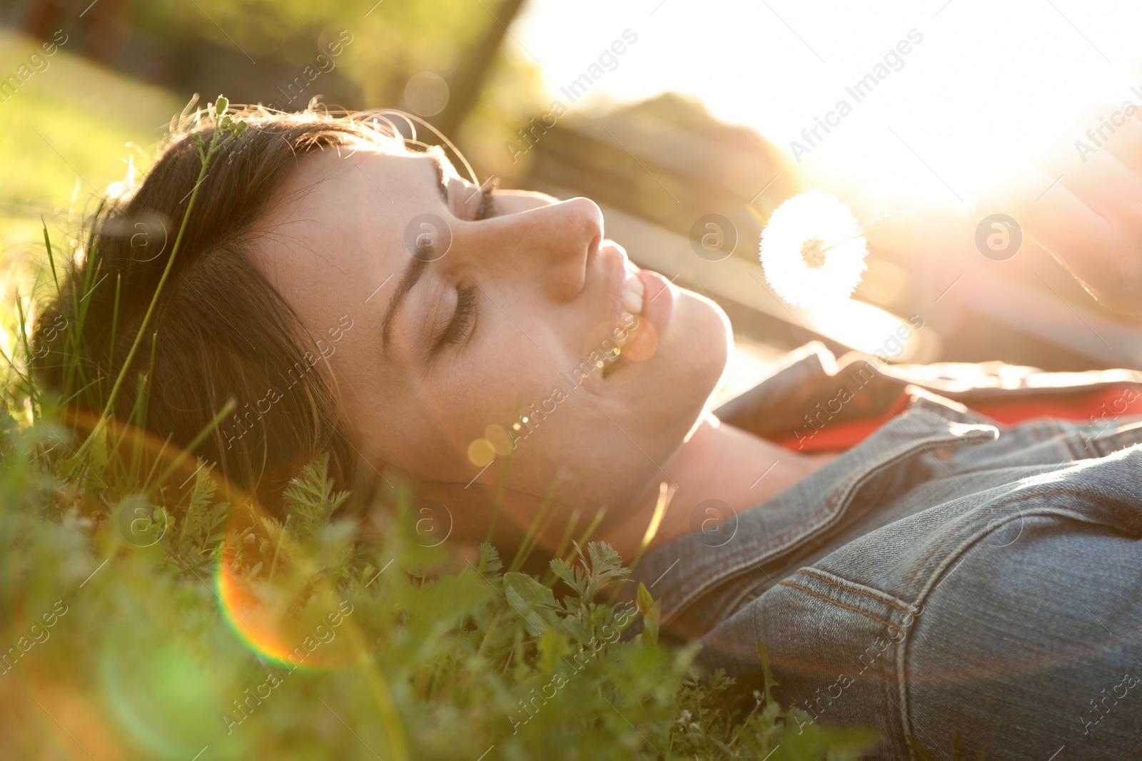 Photo of Young woman with dandelion in park on sunny day. Allergy free concept