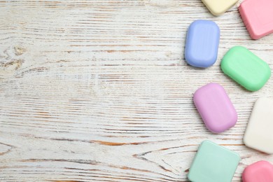 Many different soap bars on wooden table, flat lay. Space for text