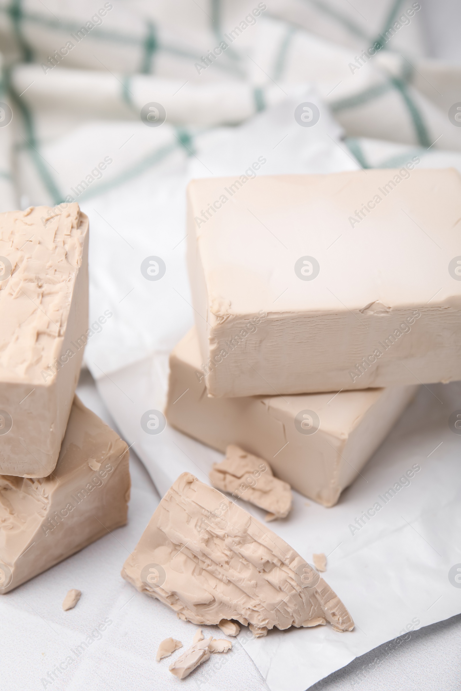 Photo of Blocks of compressed yeast on white table, closeup