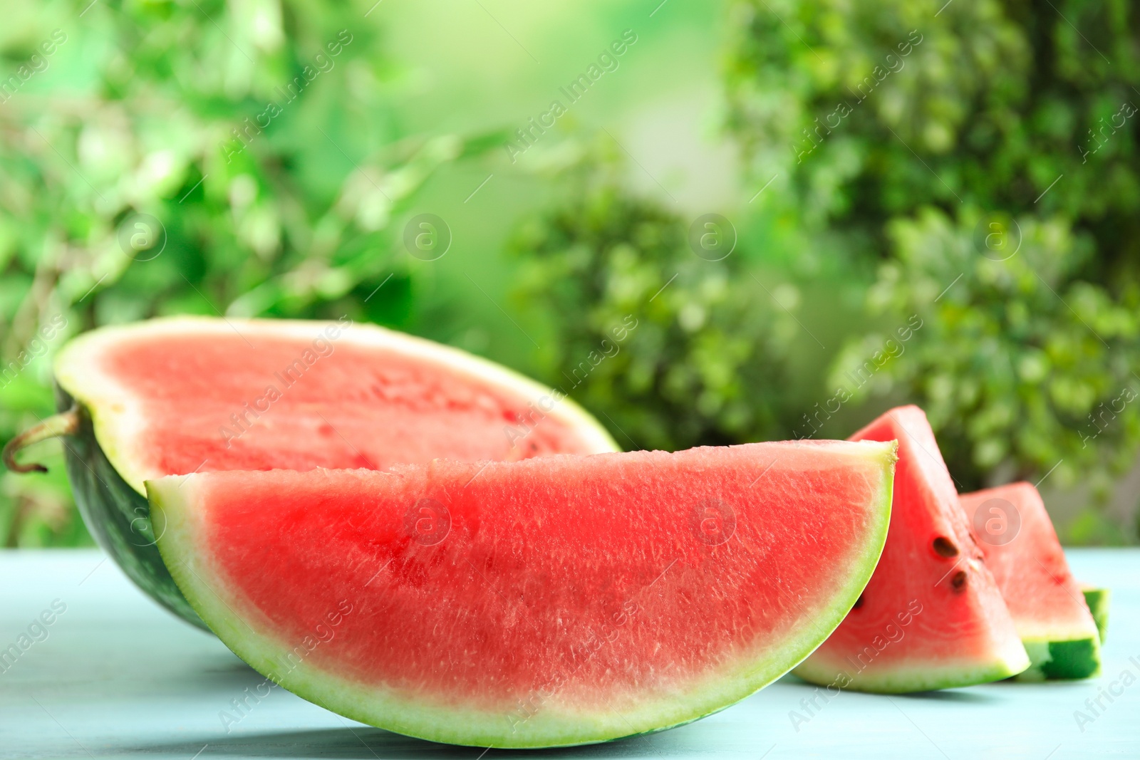 Photo of Tasty ripe cut watermelon on light blue wooden table