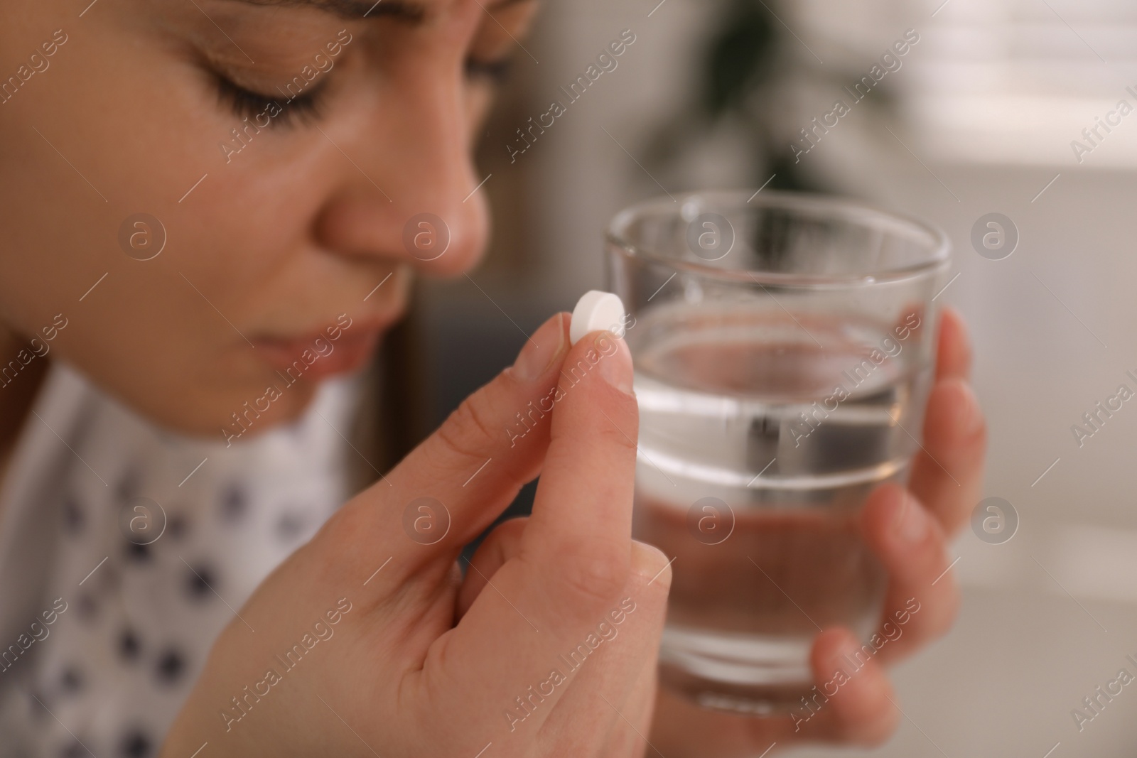 Photo of Sad young woman taking abortion pill indoors, closeup