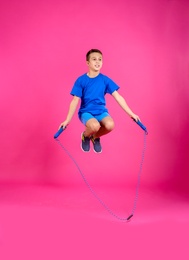 Photo of Full length portrait of boy jumping rope on color background