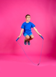 Full length portrait of boy jumping rope on color background