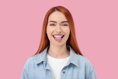 Happy woman showing her tongue on pink background