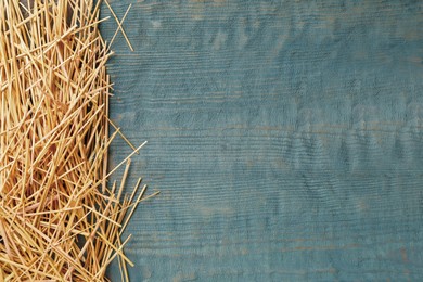 Photo of Heap of dried hay on light blue wooden background, flat lay. Space for text