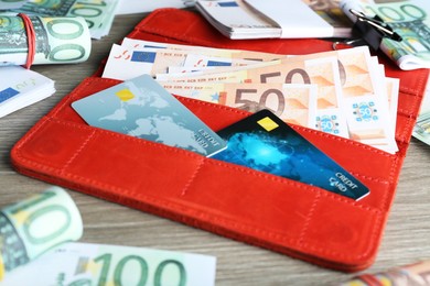 Wallet with different Euro banknotes and credit cards on wooden table, closeup. Money exchange