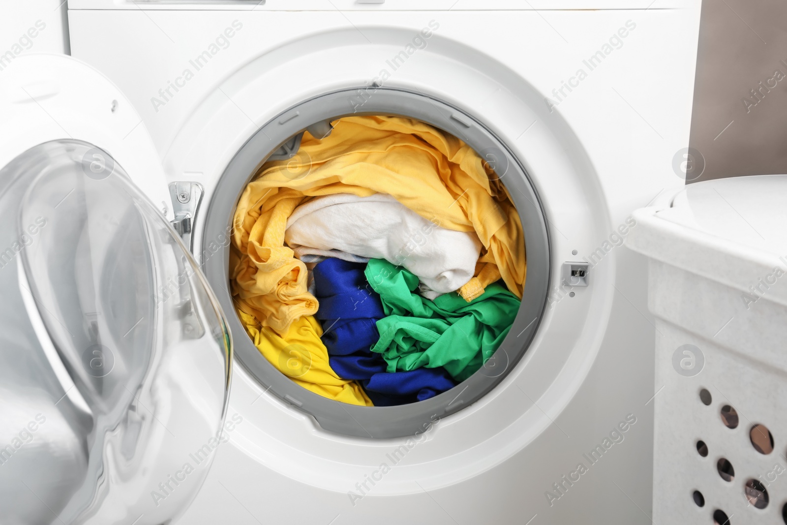 Photo of Washing machine with clothes, closeup. Laundry day