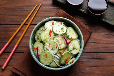 Photo of Dish with fresh creamy cucumber salad served on wooden background