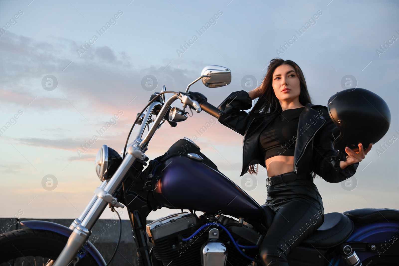 Photo of Beautiful young woman with helmet sitting on motorcycle outdoors