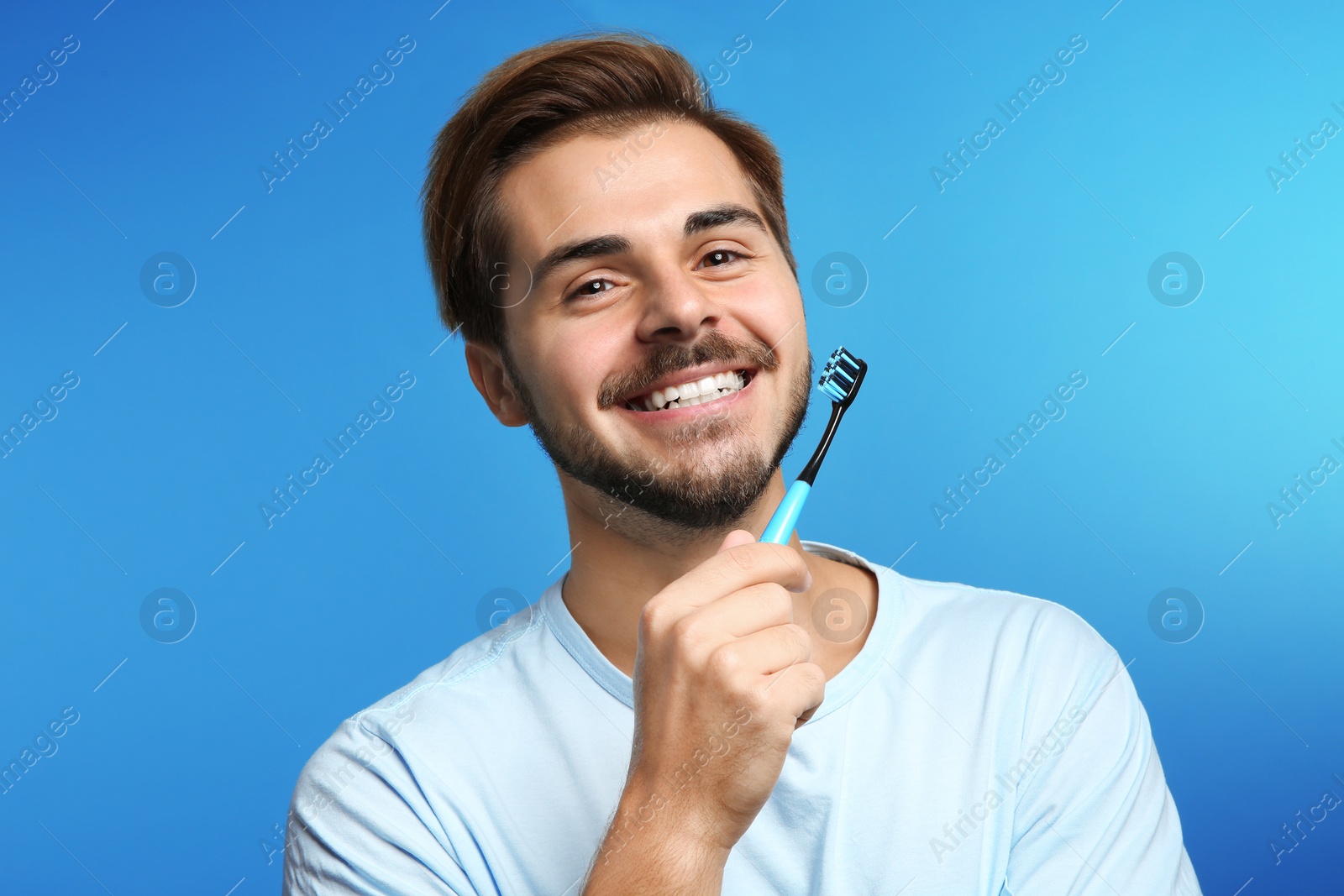 Photo of Portrait of young man with toothbrush on color background