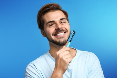 Portrait of young man with toothbrush on color background