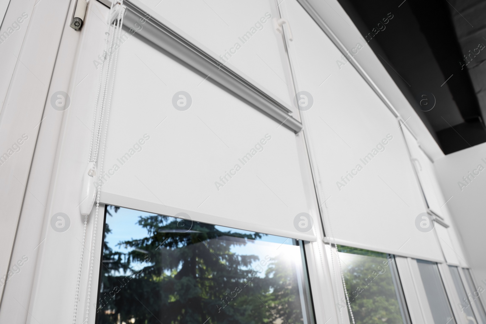 Photo of Large window with white roller blinds indoors, low angle view