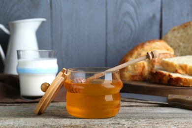 Jar of honey, milk and bread on rustic wooden table