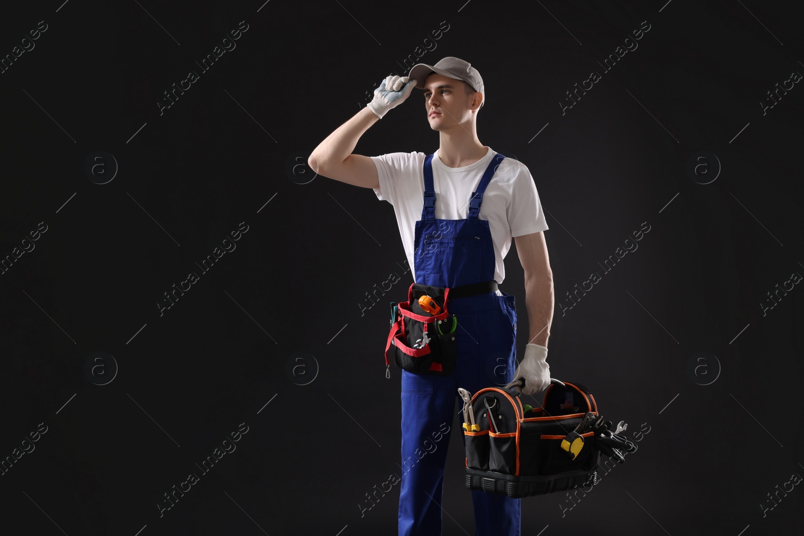 Photo of Professional repairman with tool box on black background. Space for text