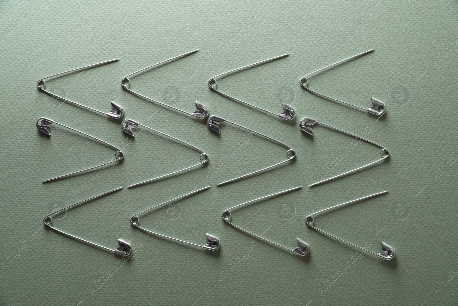 Photo of Many safety pins on green background, flat lay