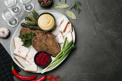 Photo of Tasty salt pork with rye bread and sauces served on grey table, flat lay. Space for text