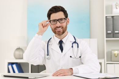 Medical consultant with glasses and stethoscope at table in clinic