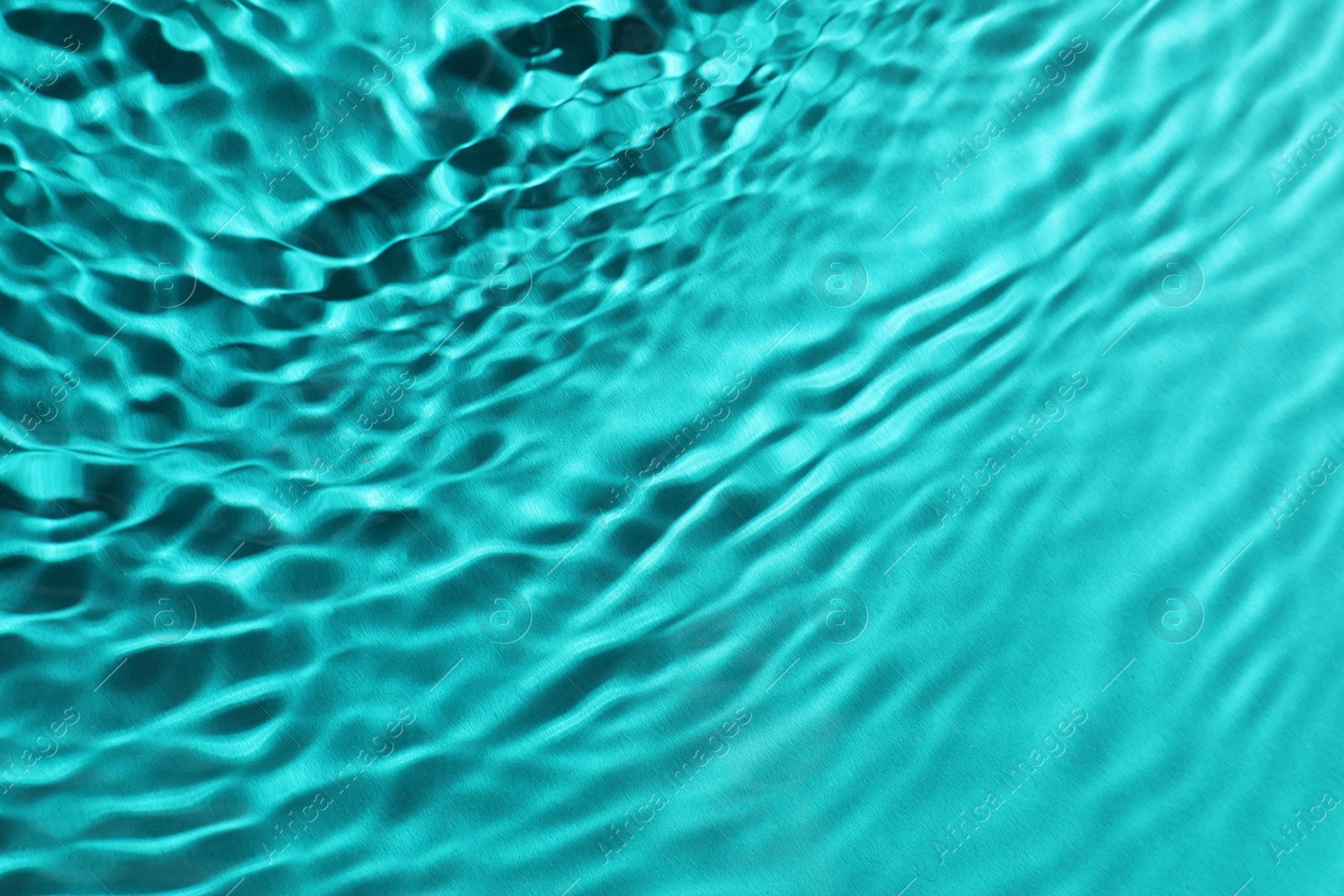 Image of Rippled surface of clear water on light blue background, closeup