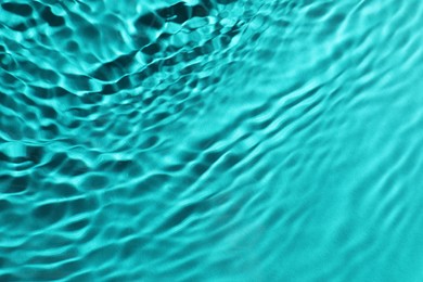 Rippled surface of clear water on light blue background, closeup