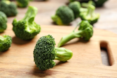 Photo of Wooden board with fresh broccoli florets on table, closeup. Space for text