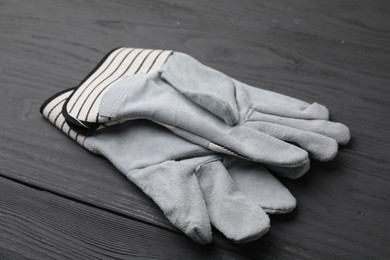 Photo of Pair of color gardening gloves on grey wooden table, closeup