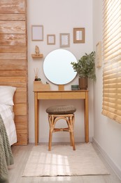 Stylish dressing table and mirror near white wall in bedroom. Interior design