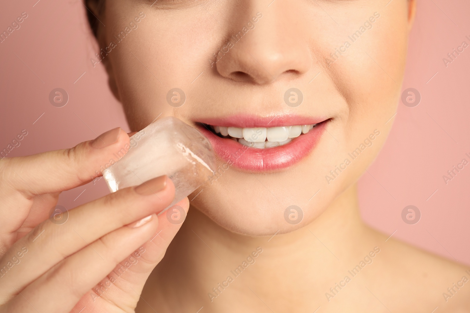 Photo of Young woman with ice cube on color background, closeup. Skin care