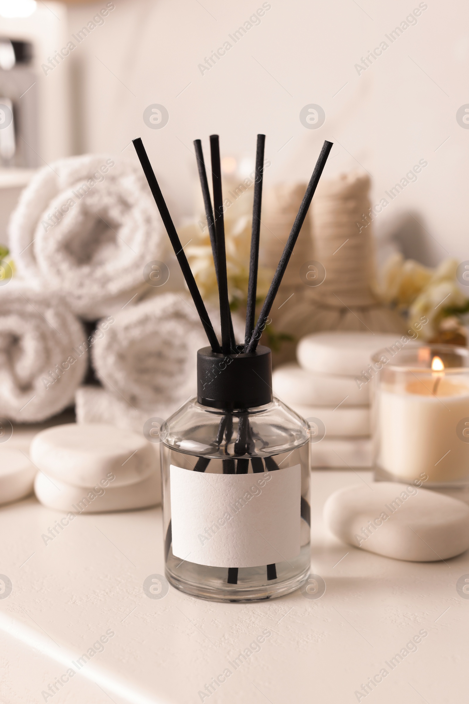 Photo of Aromatic reed air freshener and spa stones on white table