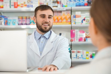 Photo of Professional pharmacist working with customer in modern drugstore