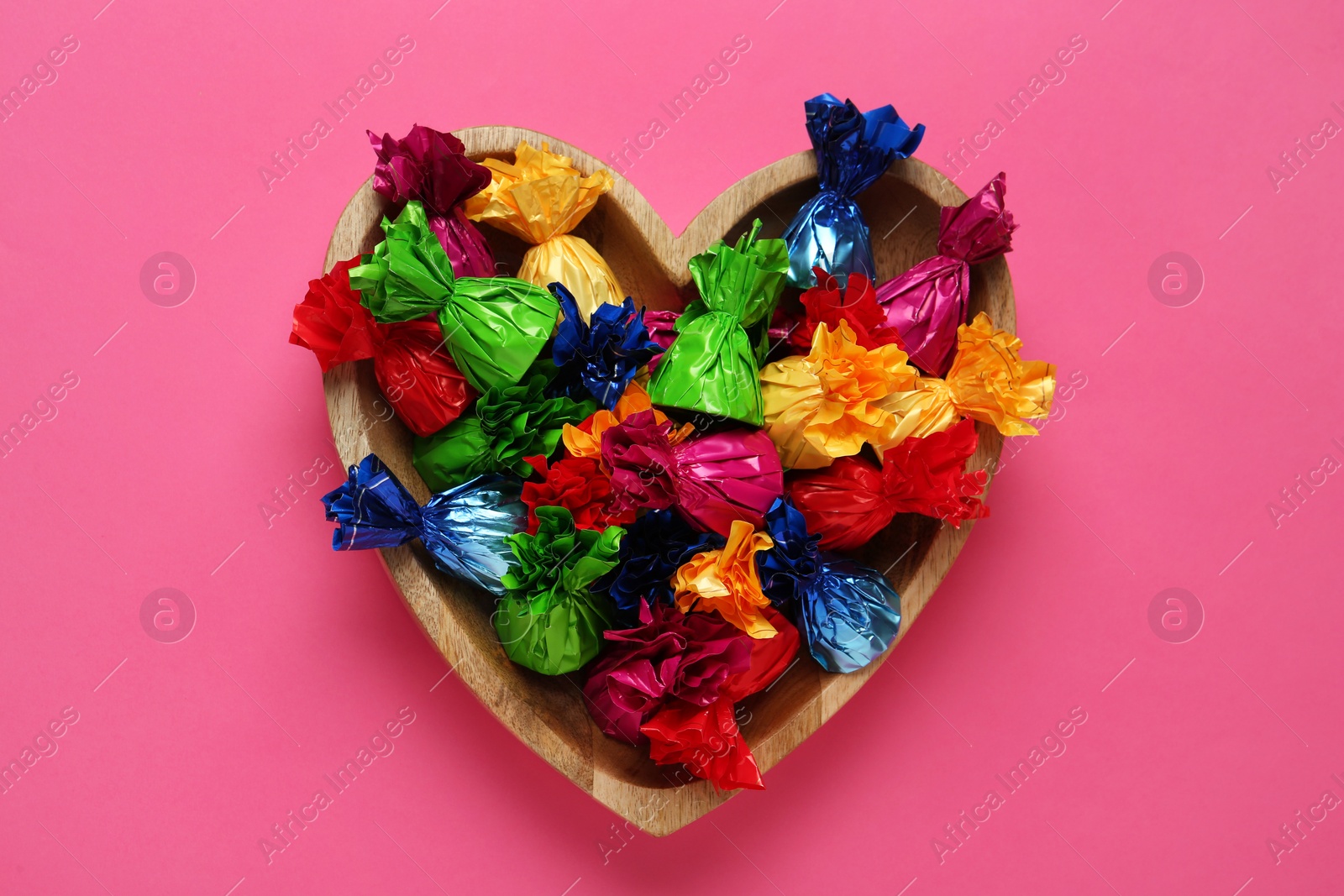 Photo of Candies in colorful wrappers on pink background, top view