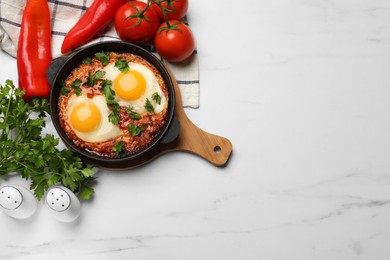 Photo of Flat lay composition with delicious shakshuka in frying pan on white marble table. Space for text