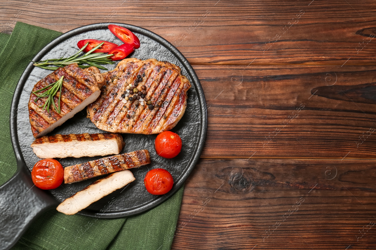 Photo of Grilled pork steaks with rosemary, spices and vegetables on wooden table, top view. Space for text